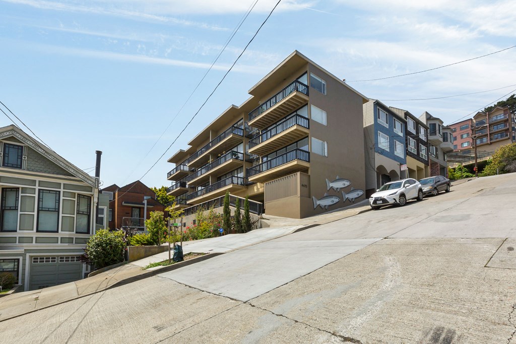 an apartment building on a city street with a car parked