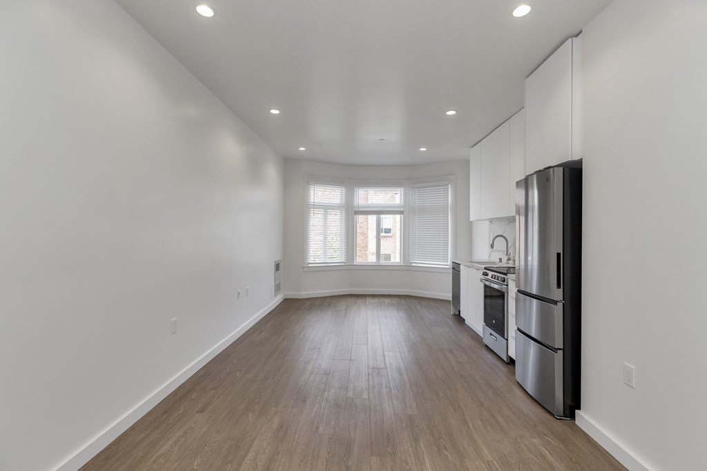 A kitchen with white walls and wooden floors.