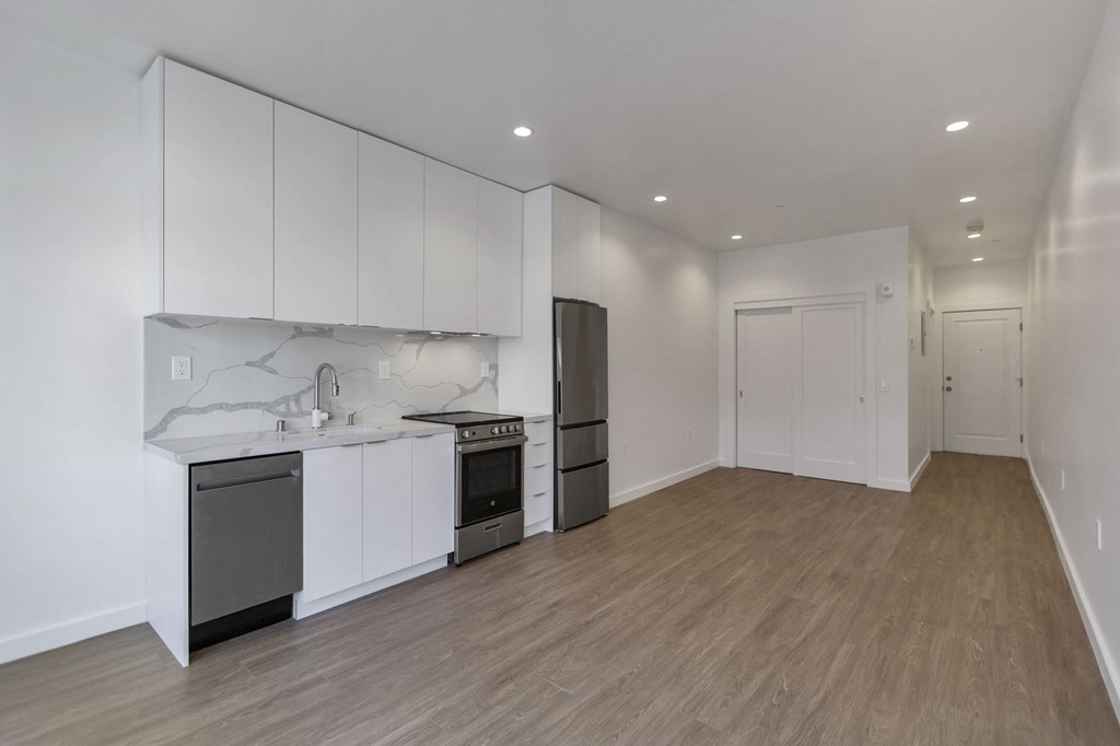 A kitchen with white cabinets and a wooden floor.