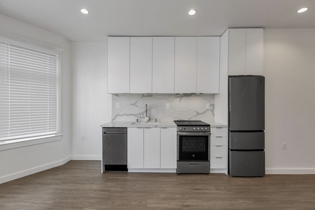 A kitchen with white cabinets and a marble backsplash.