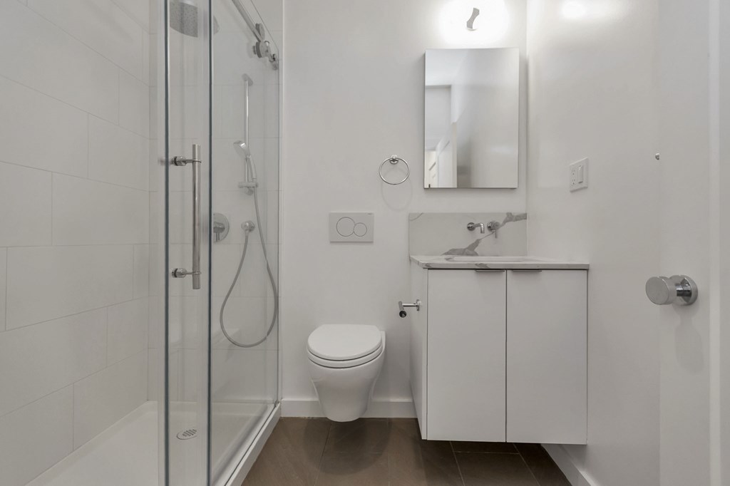 A white bathroom with a toilet, sink, and shower.