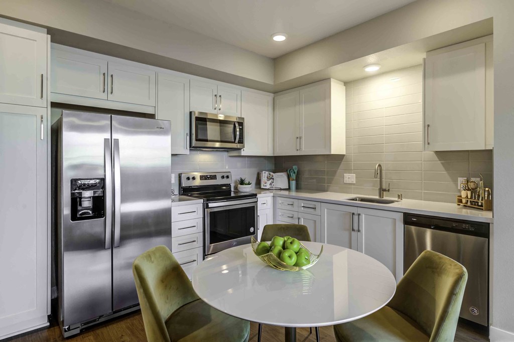 a kitchen with white cabinets and stainless steel appliances