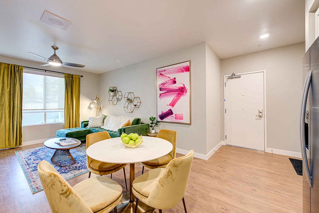 a dining area with a round table and four chairs and a living room with a green couch