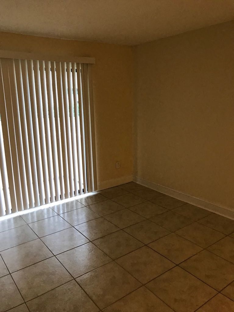 an empty room with a tiled floor and blinds on the window
