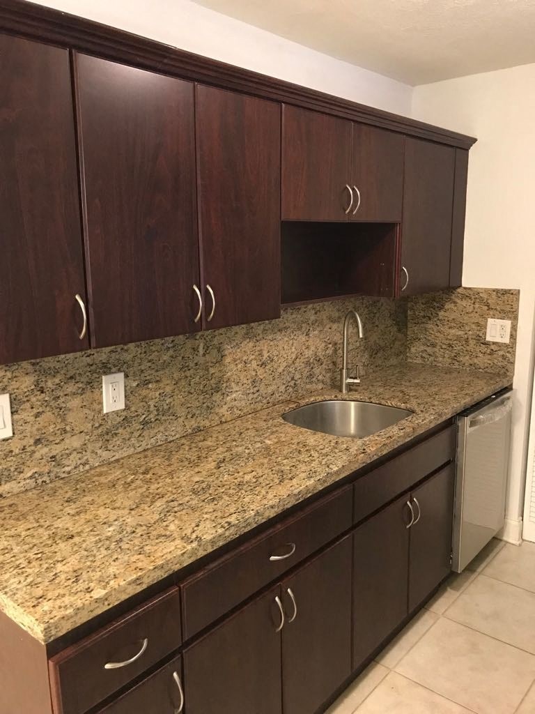 an empty kitchen with granite counter tops and wooden cabinets