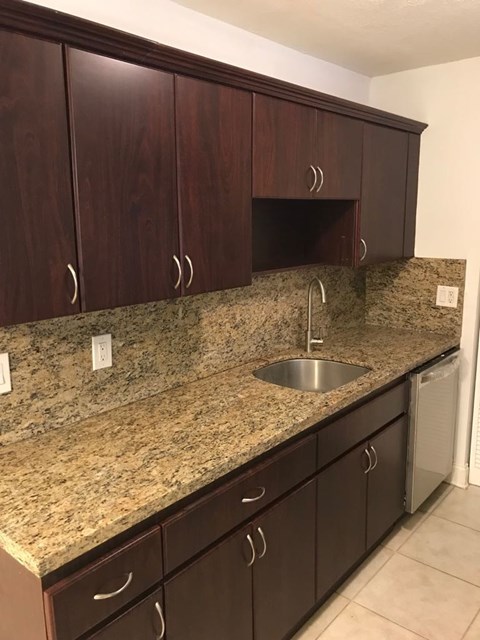 A kitchen with brown cabinets and granite countertops.