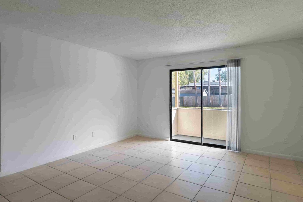 an empty living room with a tiled floor and a sliding glass door