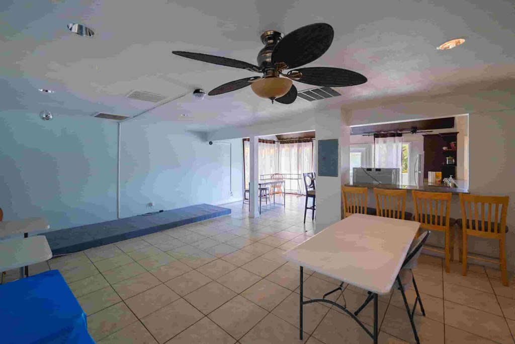 a large living room with a ceiling fan and a table