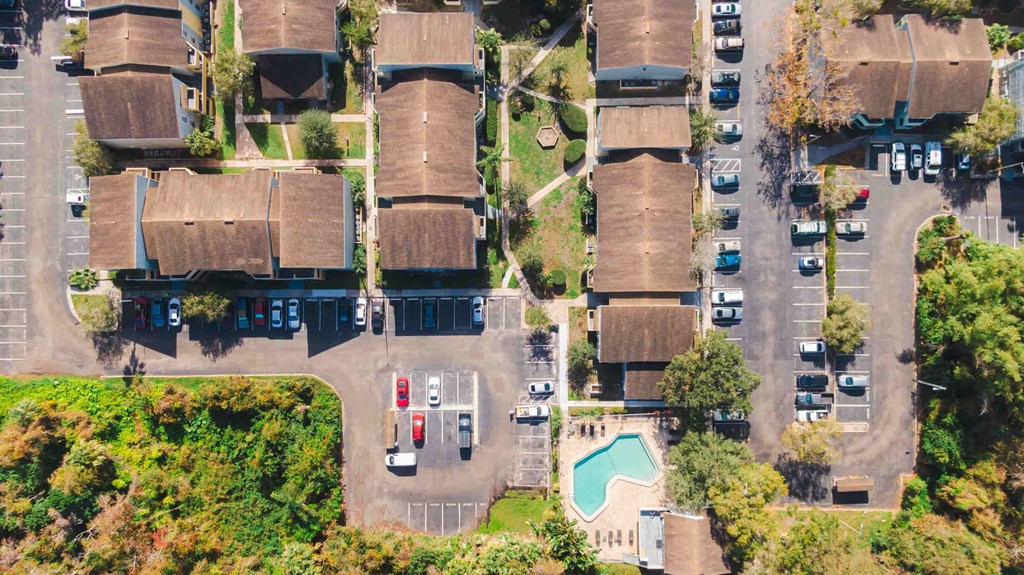 an aerial view of a parking lot with houses and trees