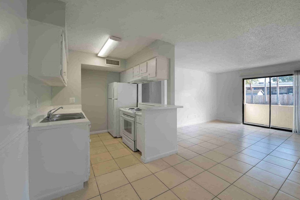 an empty kitchen with white cabinets and a refrigerator and a sink
