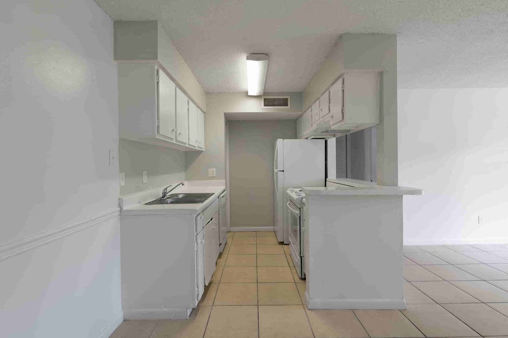 a kitchen with white cabinets and a refrigerator and a sink