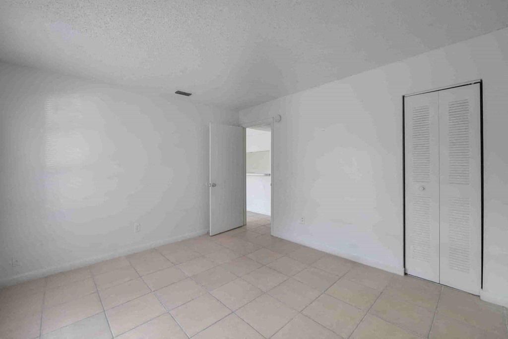 an empty living room with white walls and a door to a hallway