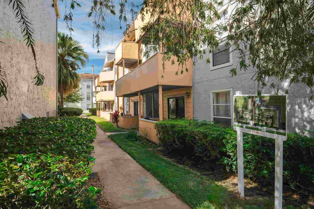 a sidewalk in front of an apartment building with a sign