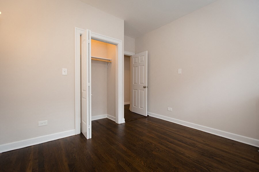 an empty living room with wood floors and a door to a closet