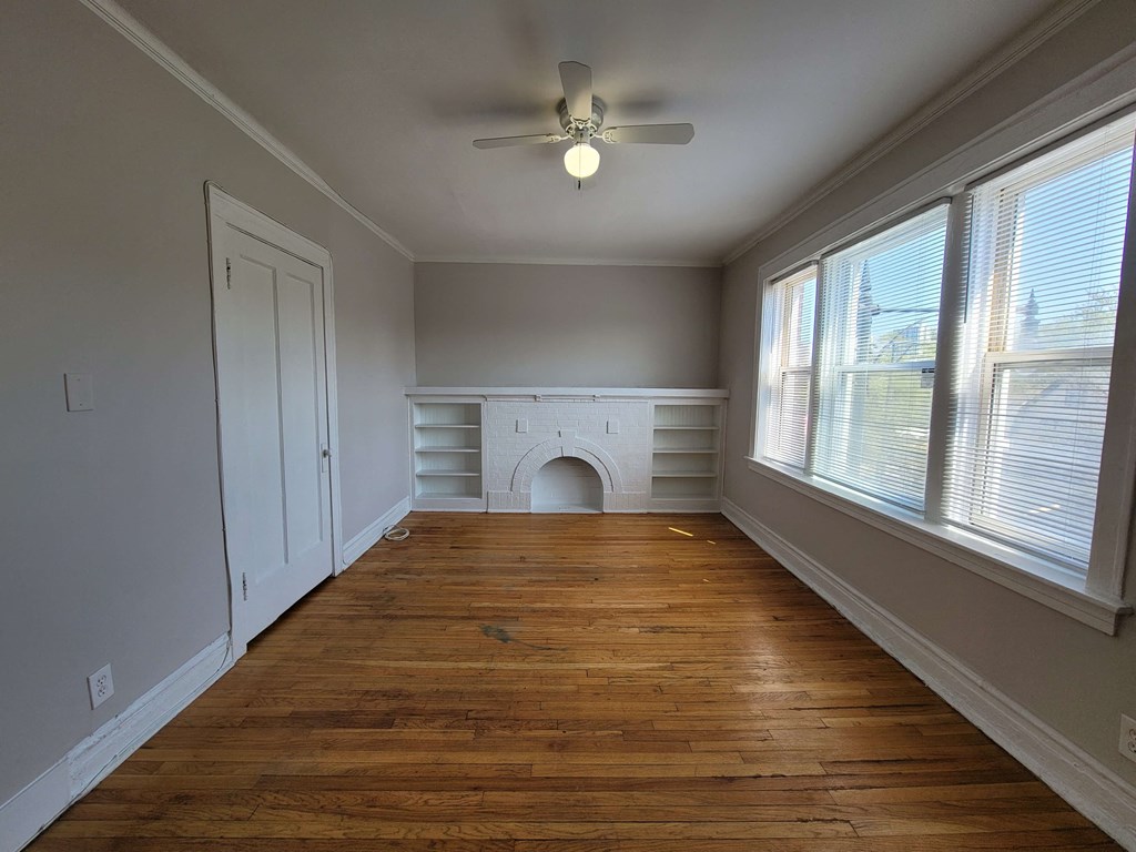 a living room with a large window and a ceiling fan