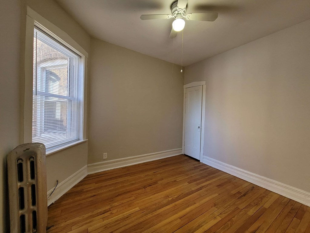 an empty living room with wood floors and a ceiling fan