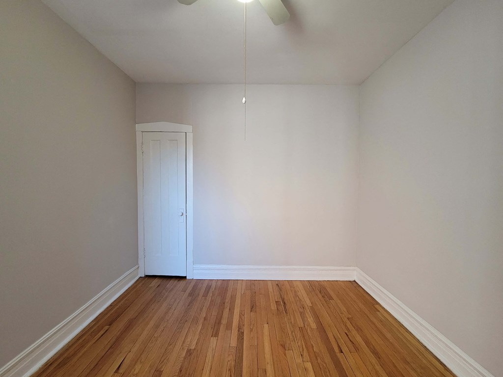 a room with white walls and wood floors and a closet