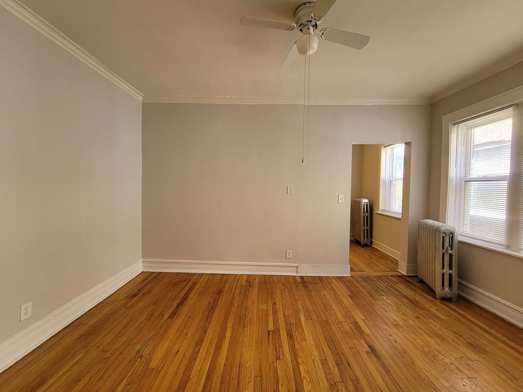 an empty living room with wood floors and a ceiling fan