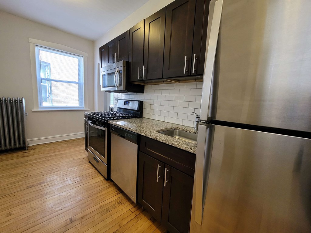a kitchen with stainless steel appliances and wooden floors