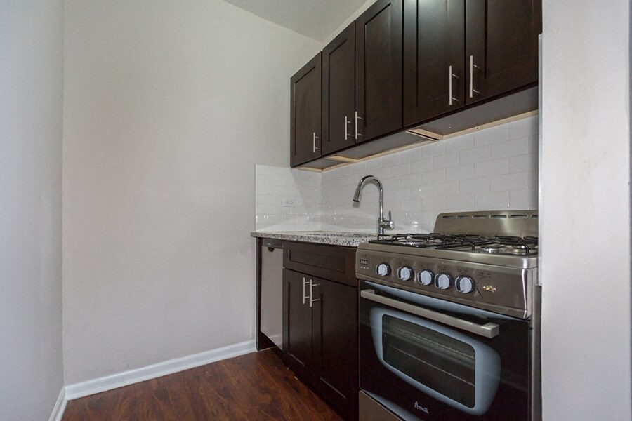 an empty kitchen with black cabinets and a stove and sink