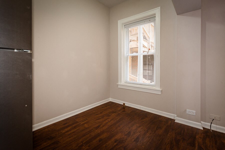 an empty room with a window and wooden floors