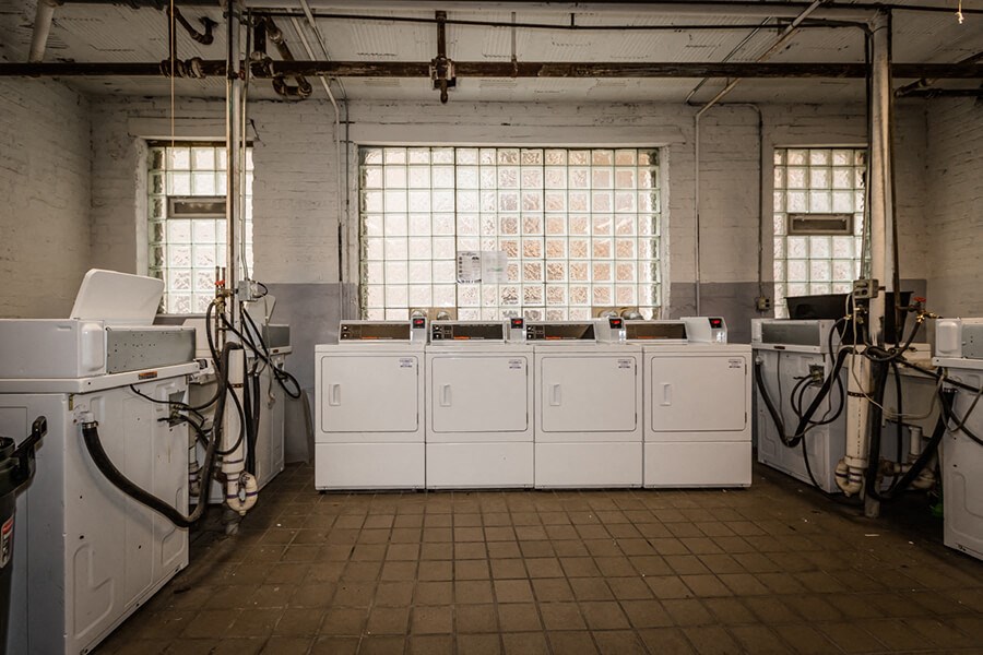 a row of white washing machines in an old laundry room