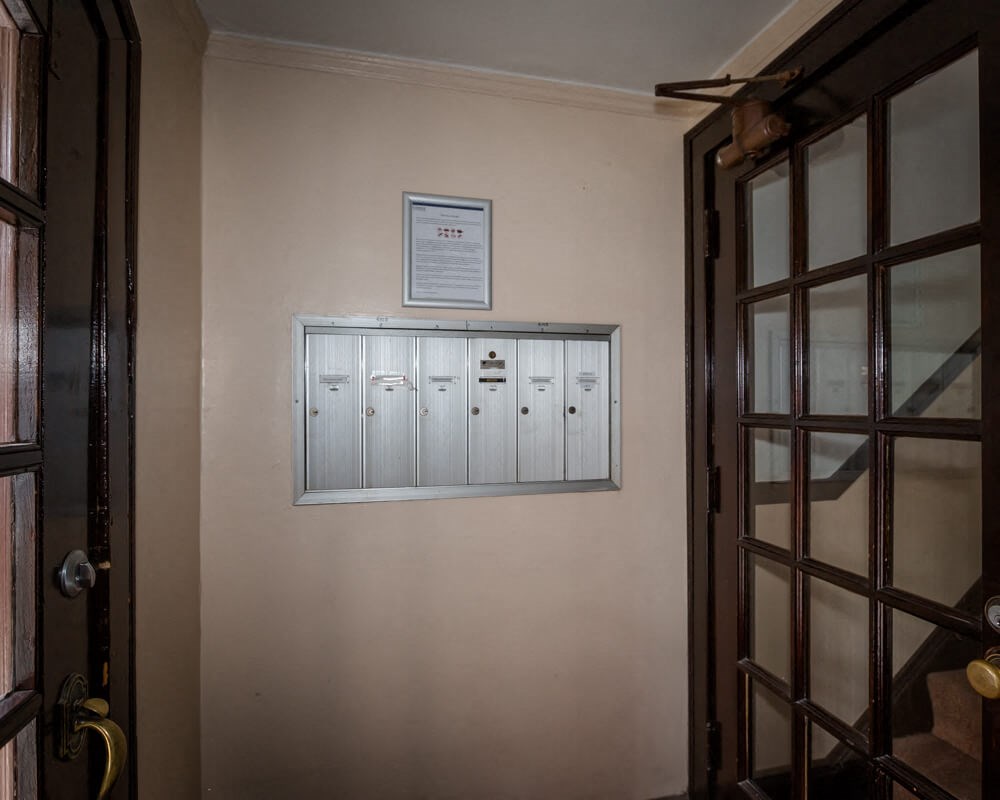 the front door of a building with mailboxes and a sign on the wall