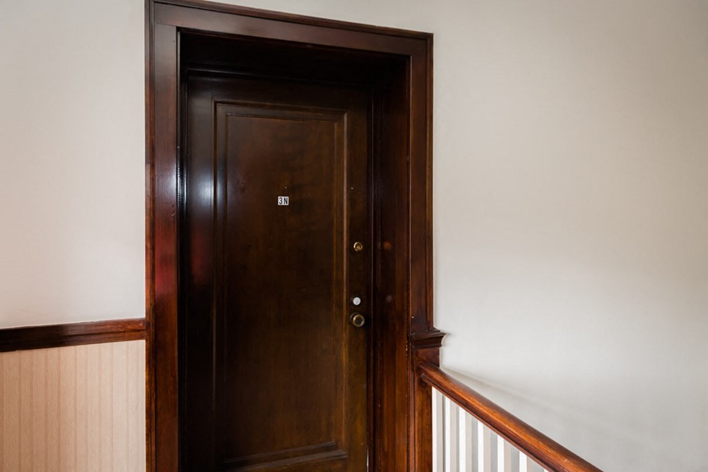 a wooden door in a room with a white wall and a staircase