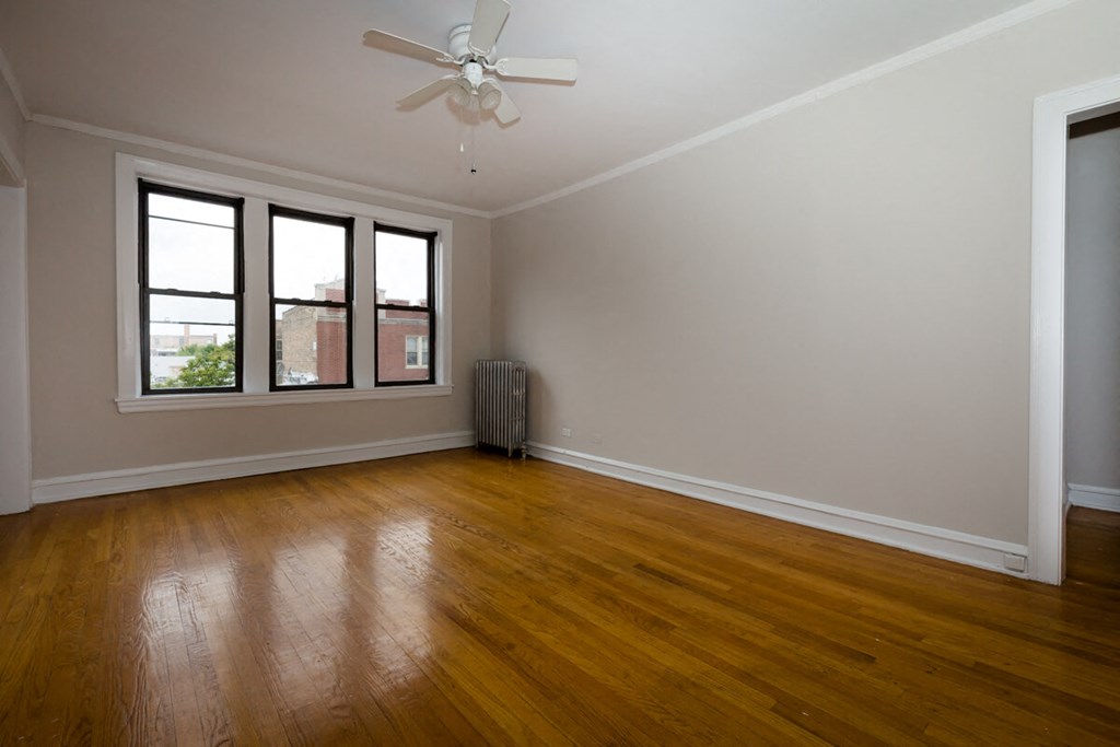 an empty living room with wood floors and a ceiling fan