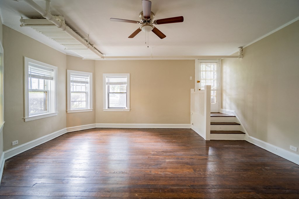 an empty living room with wood floors and a ceiling fan