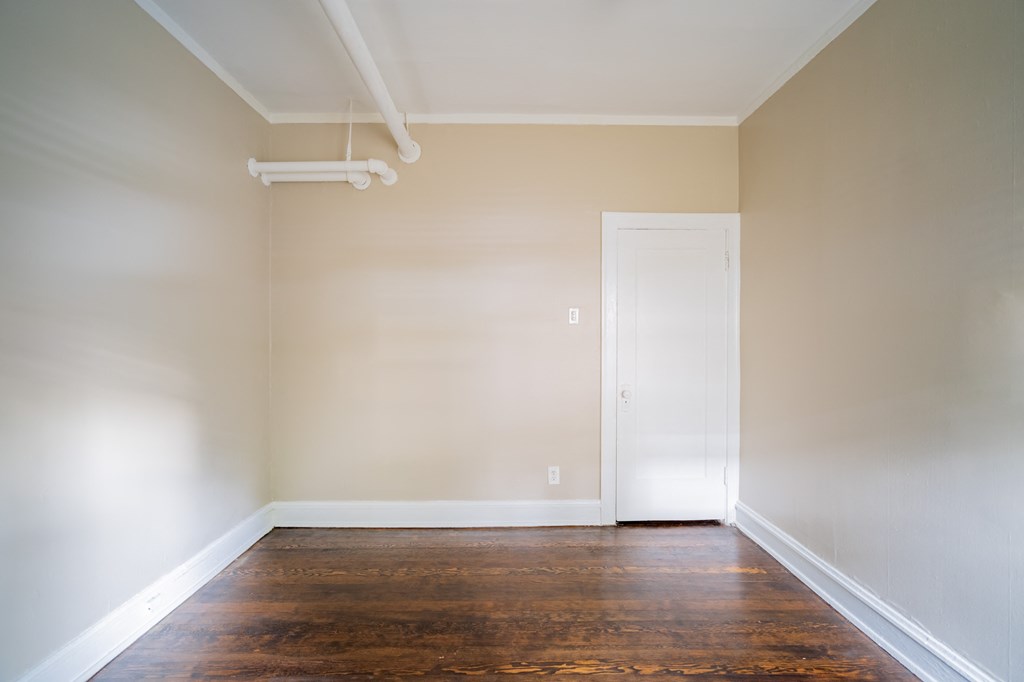 an empty room with wood floors and a white door
