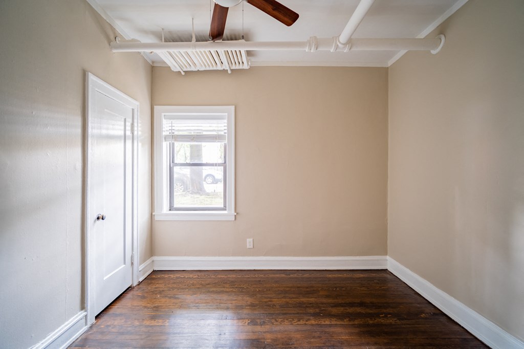 an empty living room with wooden floors and a ceiling fan
