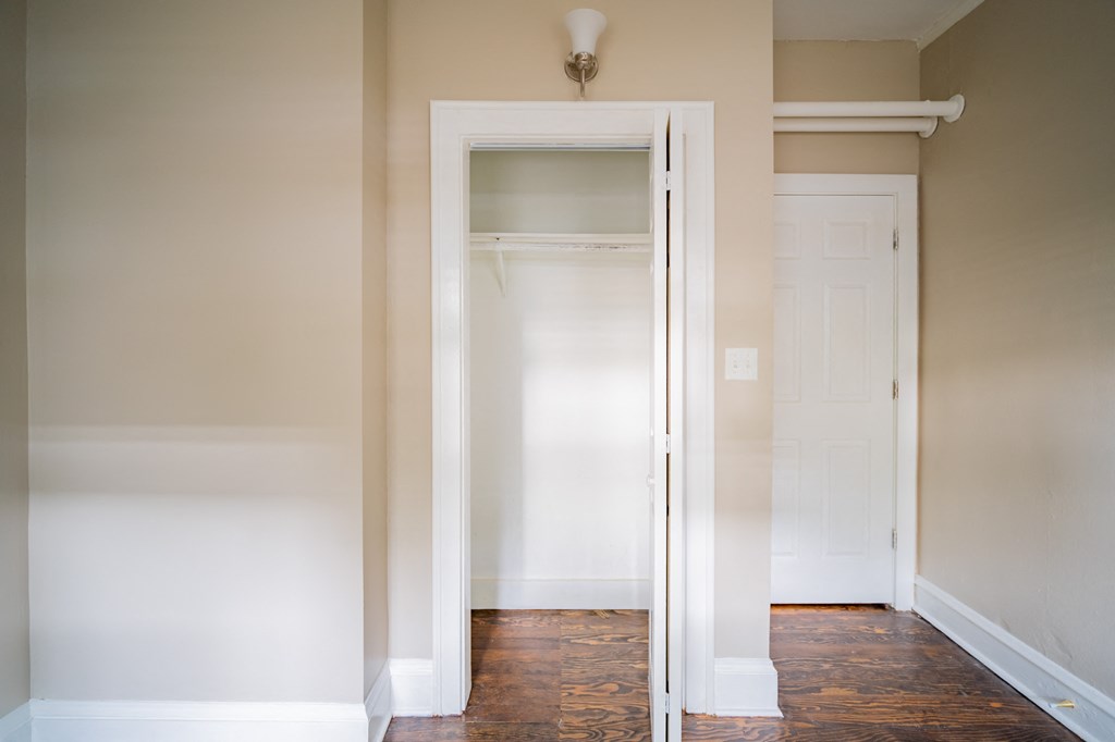 an empty hallway with a mirror and a closet door