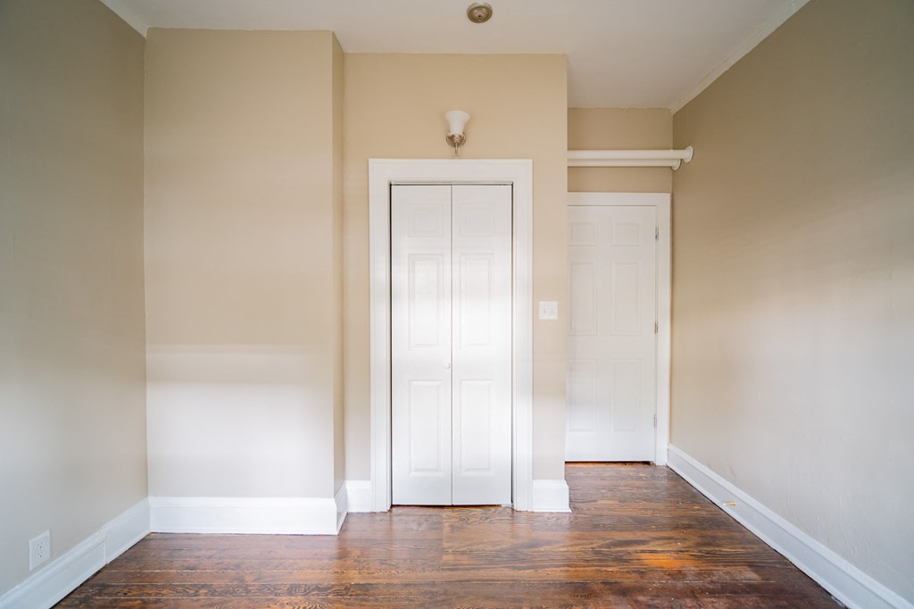 an empty room with a white door and wood floors