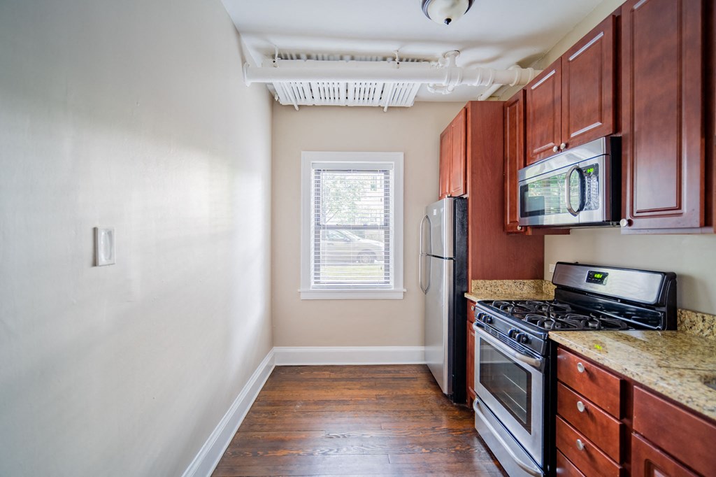 an empty kitchen with wood cabinets and a stove and refrigerator