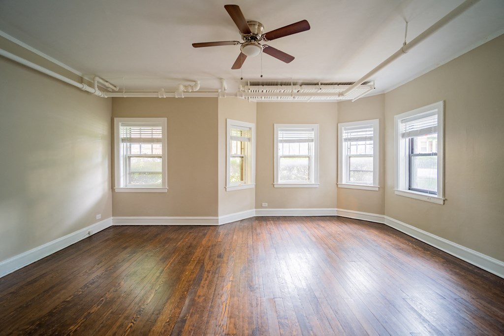 an empty living room with wood floors and a ceiling fan