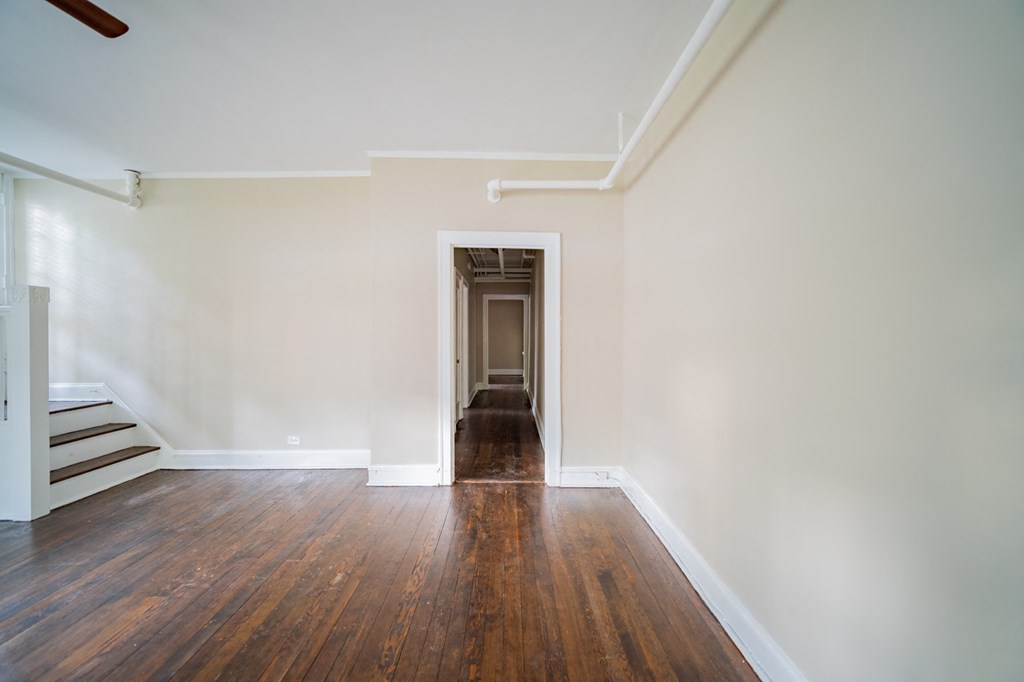 an empty living room with wood floors and white walls