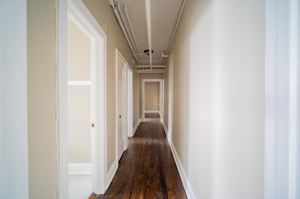 a hallway with wood floors and white walls and doors