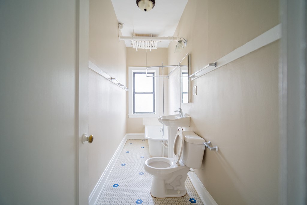 a white bathroom with a toilet and a window