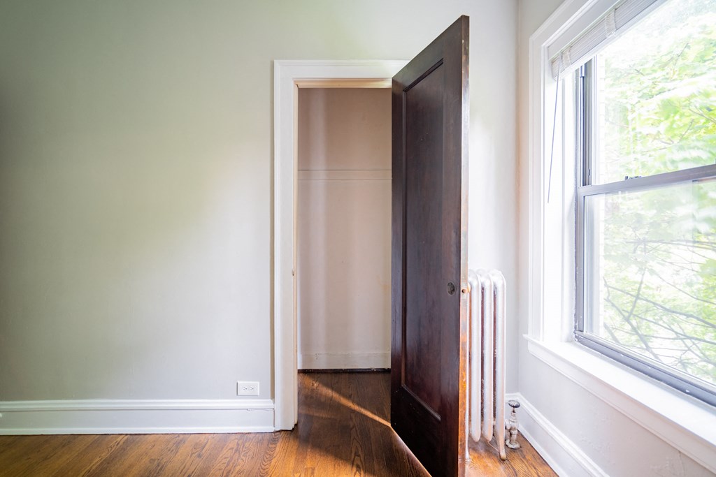 a room with a door open and a radiator and a window