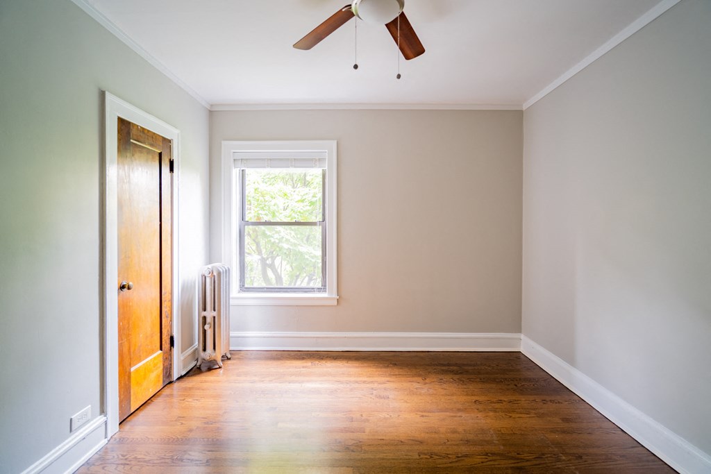an empty room with wooden floors and a ceiling fan