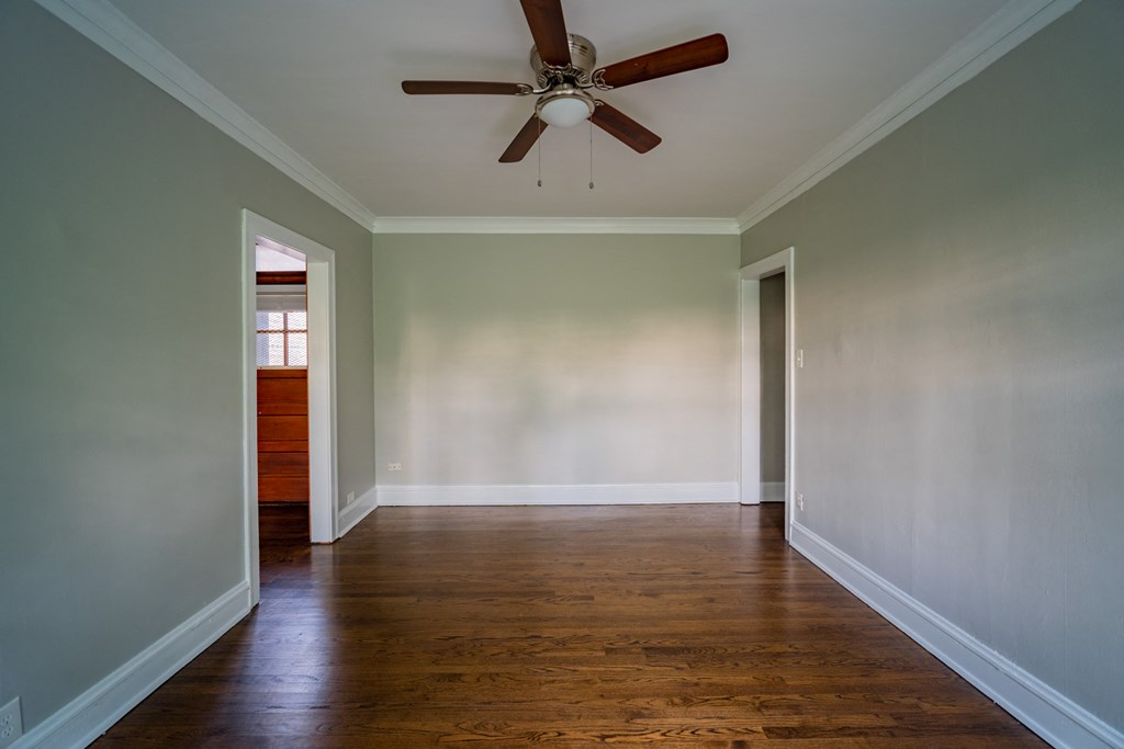 an empty living room with wood floors and a ceiling fan