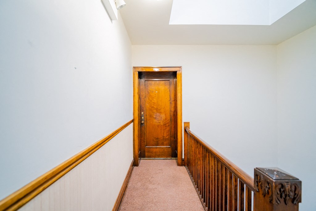 a hallway with a wooden door at the top of a staircase