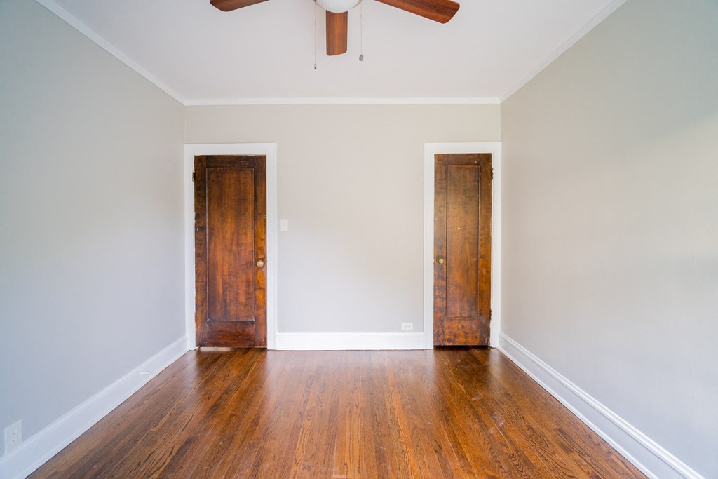 an empty room with wooden floors and a ceiling fan