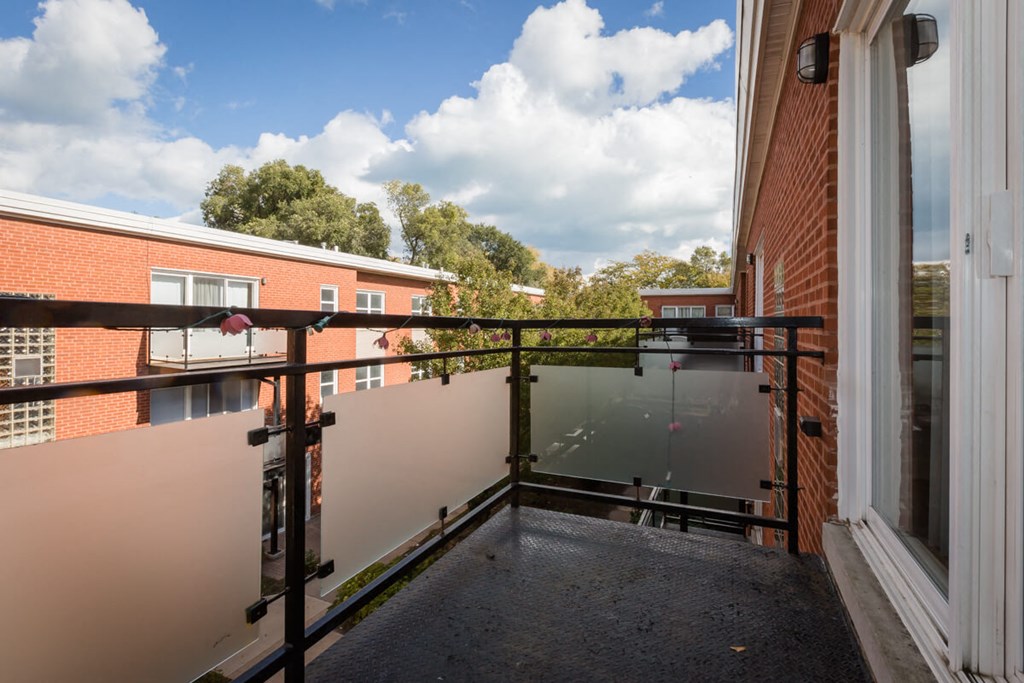 a balcony with a view of a brick building and a glass fence
