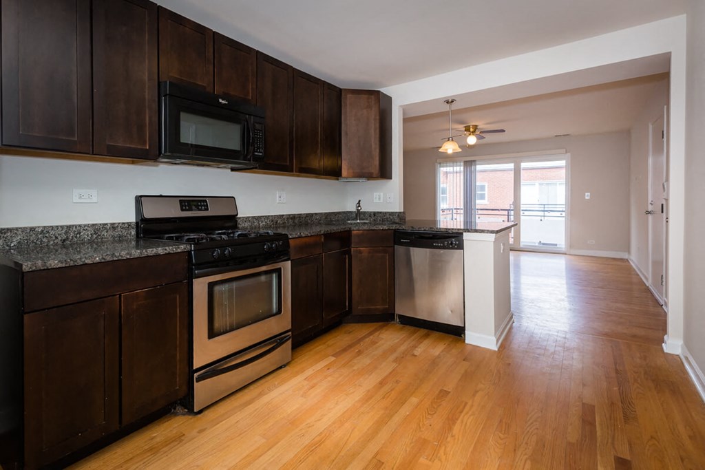 an empty kitchen with wooden floors and stainless steel appliances