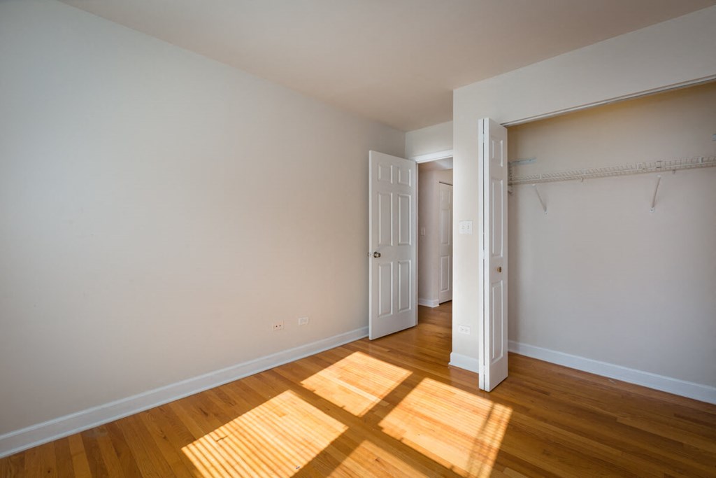 a bedroom with wood floors and white walls and a closet