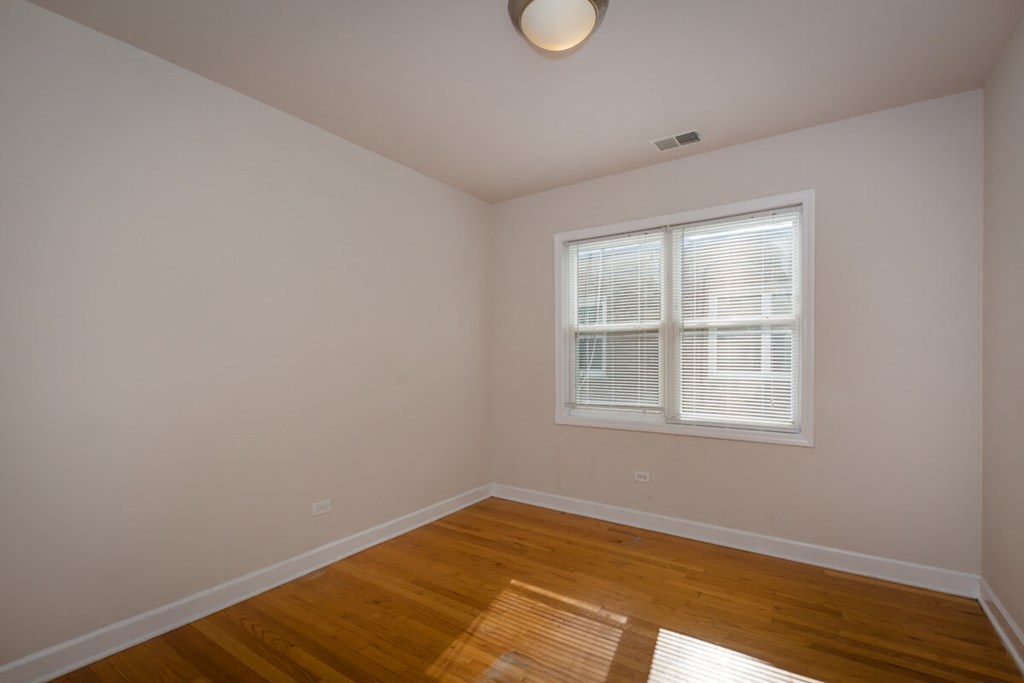 a bedroom with hardwood floors and a window
