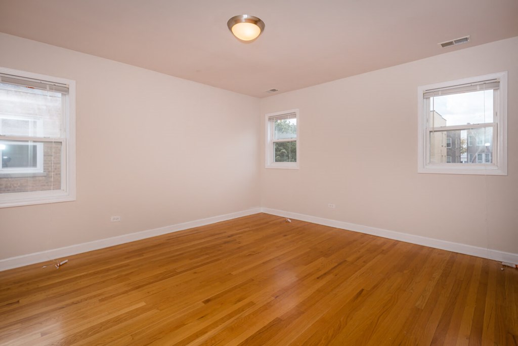 a living room with a hard wood floor and two windows