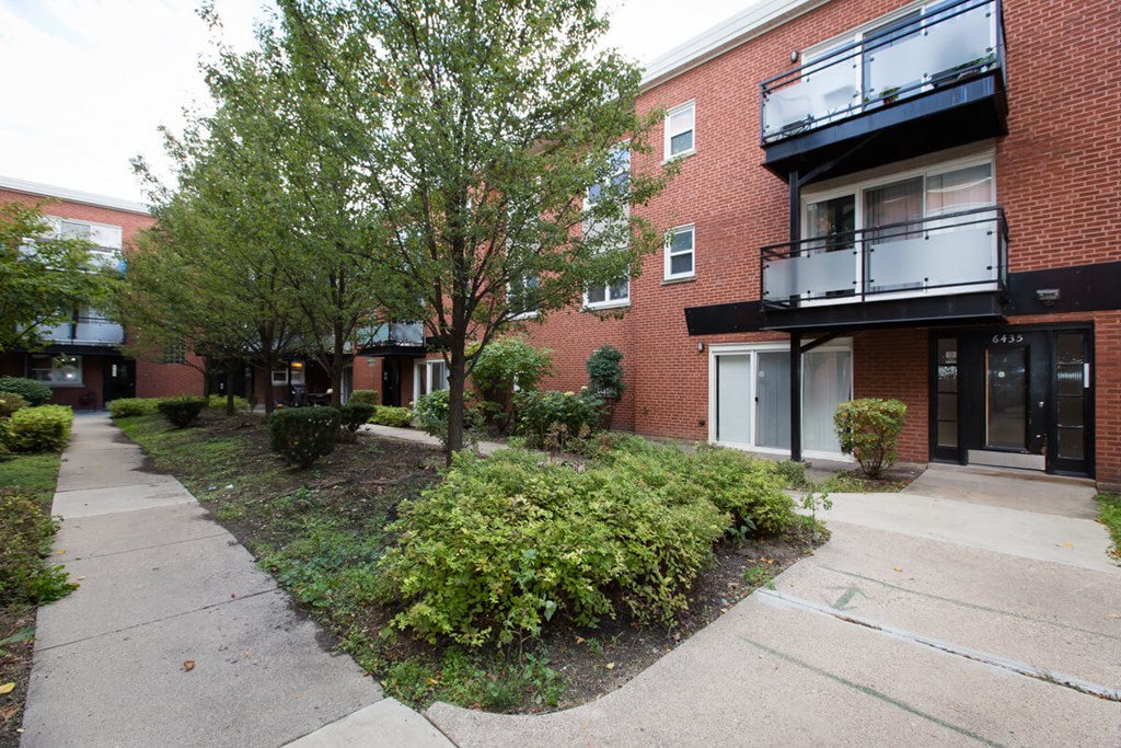 a sidewalk in front of a brick apartment building